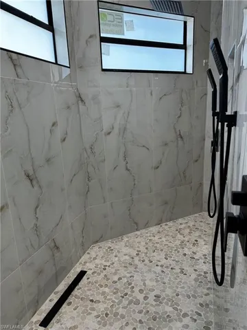 Bathroom featuring a tile shower and plenty of natural light