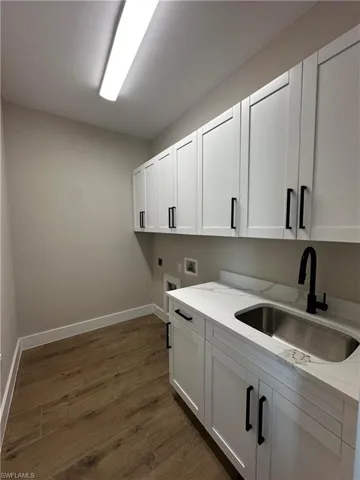 Laundry area with cabinets, sink, electric dryer hookup, dark hardwood / wood-style flooring, and hookup for a washing machine