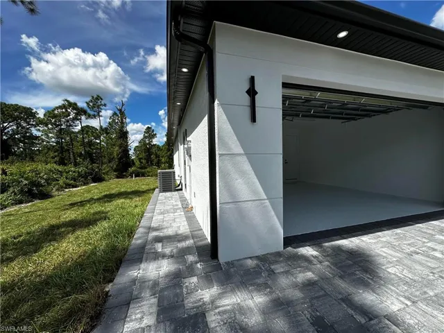View of side of home with central AC unit and a yard