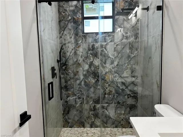 Bathroom featuring vanity, toilet, and a shower with shower door