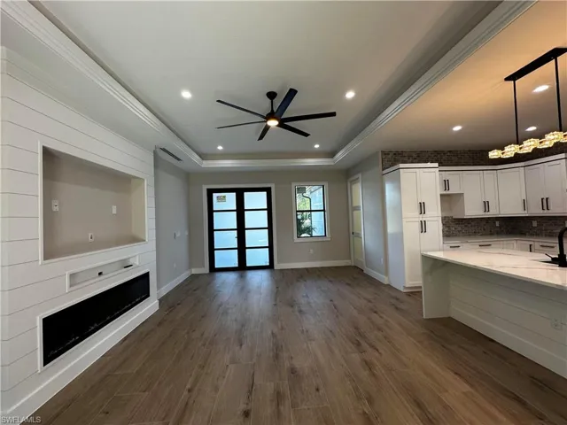 Kitchen featuring ceiling fan, white cabinets, light stone counters, pendant lighting, and dark wood-type flooring