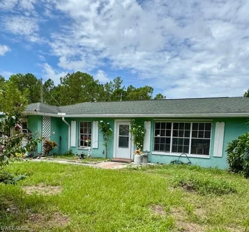 Ranch-style house featuring stucco siding, a front yard, and roof with shingles
