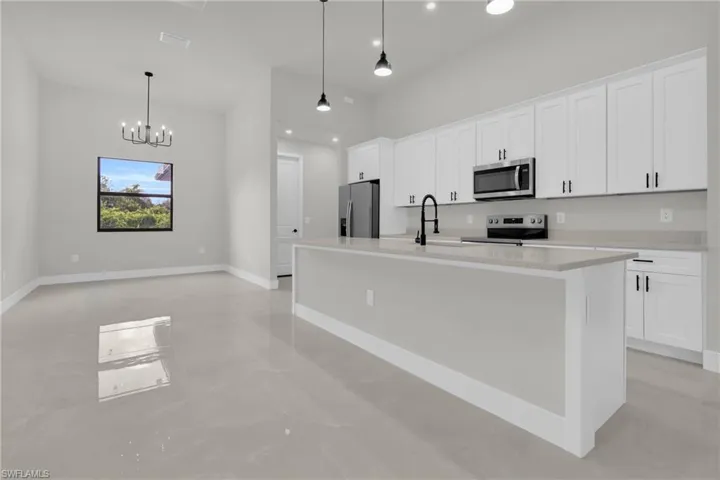 Kitchen featuring white shaker-style cabinetry, quartz countertops, a central island with a matte black faucet, and pendant lighting
