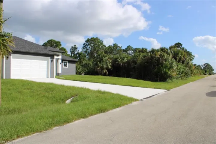 Exterior featuring horizontal lap siding, a two-car garage, concrete driveway, and expansive natural landscaping