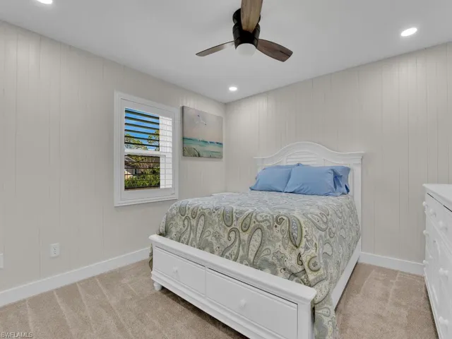 Bedroom featuring wood walls, light colored carpet, and ceiling fan