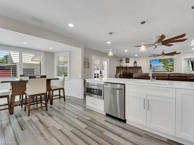 Kitchen featuring white cabinetry, appliances with stainless steel finishes, decorative light fixtures, sink, and a healthy amount of sunlight