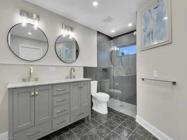 Bathroom featuring toilet, vanity, and a shower with door