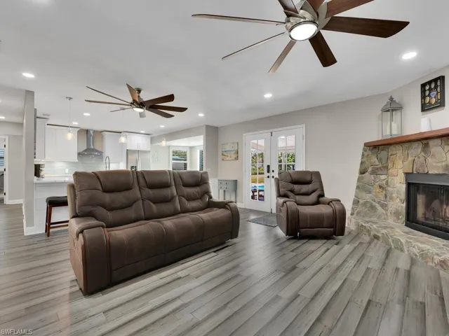 Living room featuring french doors, light wood-type flooring, a fireplace, and ceiling fan