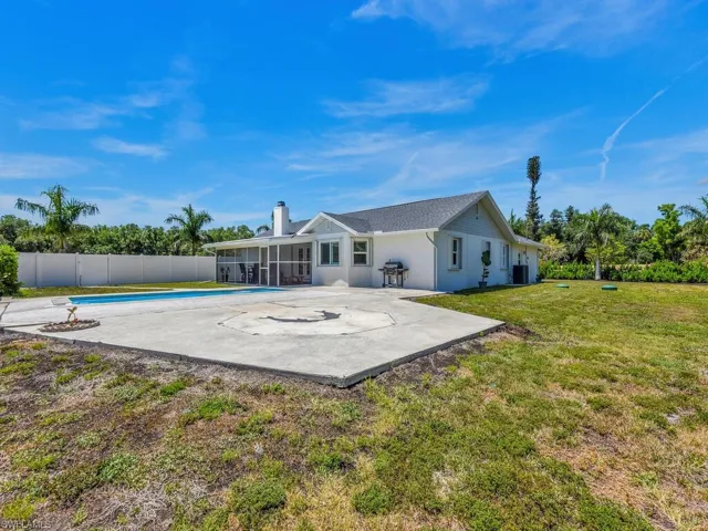 Rear view of property featuring a sunroom, a fenced in pool, a lawn, cooling unit, and a patio area
