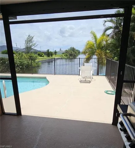Screened patio featuring a curved swimming pool, expansive pool deck, and black metal fencing