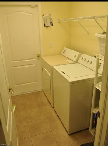 Dedicated laundry area featuring ceramic tile flooring, neutral wall tones, and a wall-mounted wire shelf for organization
