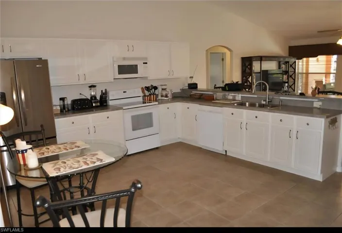 Spacious kitchen featuring extensive white cabinetry, a double basin sink, and a full suite of appliances