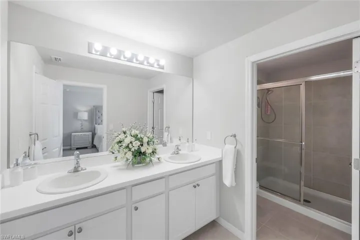 Full bath featuring a shower stall, ensuite bath, double vanity, and light tile patterned floors