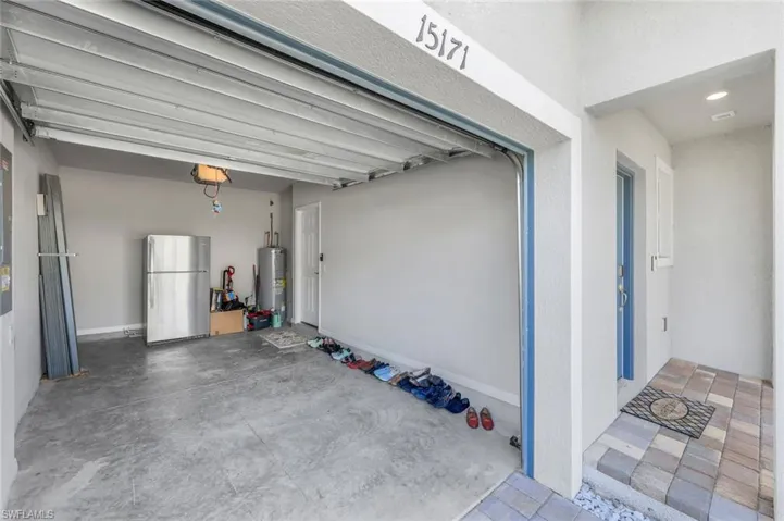 Garage featuring freestanding refrigerator and electric water heater