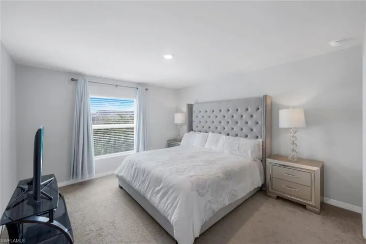Bedroom featuring light carpet and baseboards