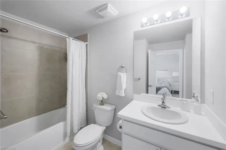Bathroom featuring shower / bath combo with shower curtain, ensuite bathroom, vanity, and light tile patterned floors