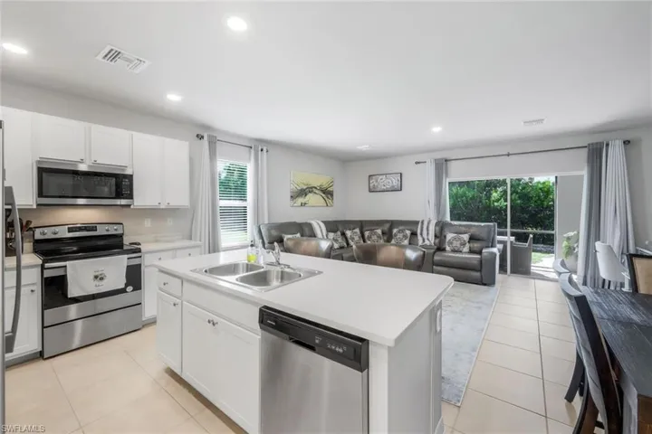 Kitchen featuring stainless steel appliances, white cabinetry, open floor plan, light countertops, and recessed lighting