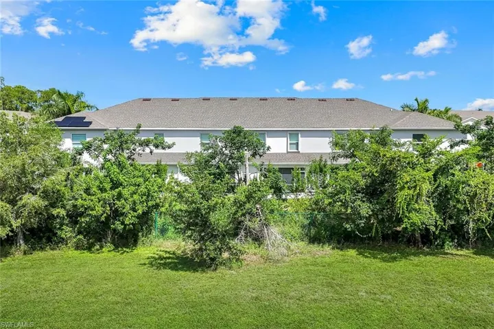 Rear view of house featuring a lawn and roof with shingles