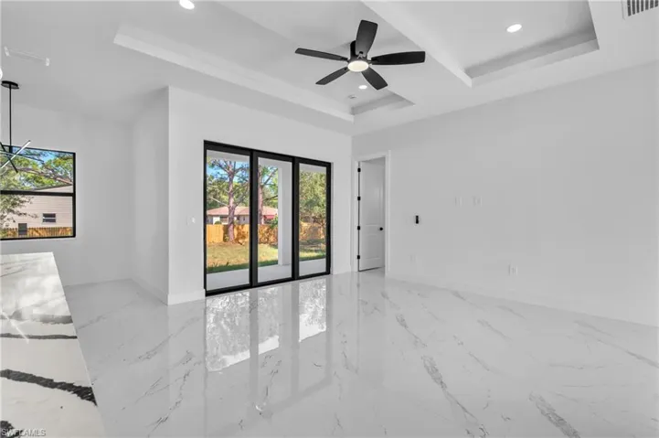 Unfurnished room with a raised ceiling, recessed lighting, a ceiling fan, and light marble finish floors