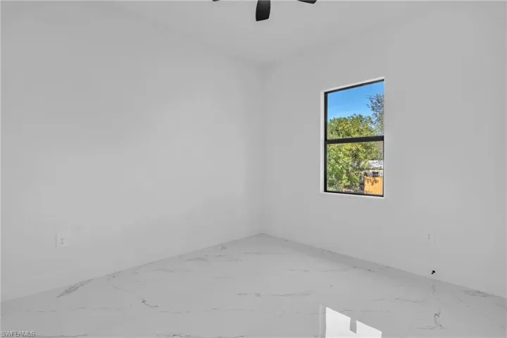 Spare room with a ceiling fan and marble finish floors