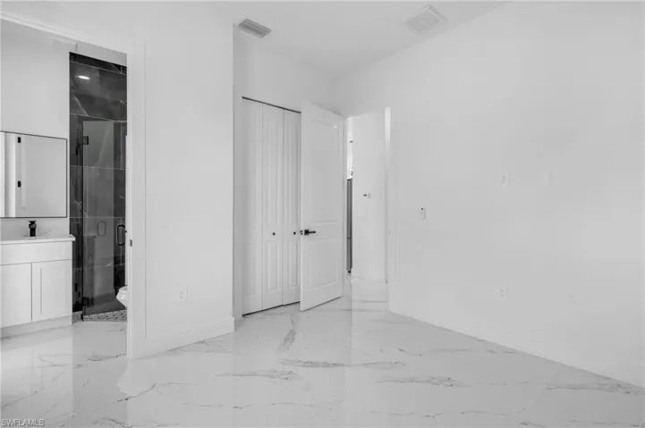 Unfurnished bedroom featuring light marble finish flooring, ensuite bath, and a closet