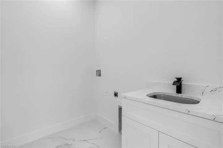 Laundry area featuring hookup for an electric dryer and light marble finish flooring