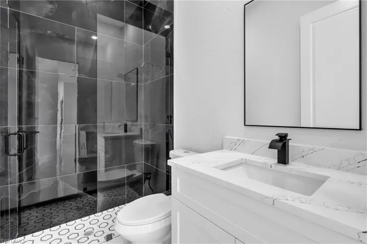 Full bathroom featuring a stall shower, vanity, and a textured wall