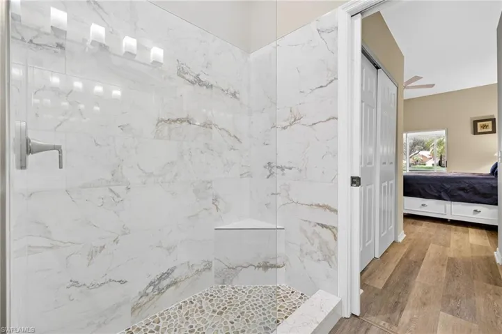 Ensuite bathroom with wood finished floors and a marble finish shower