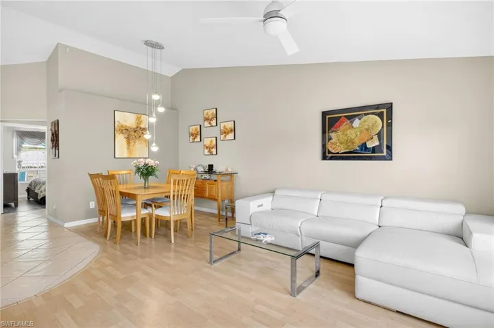 Living room with vaulted ceiling, a ceiling fan, and light wood-type flooring