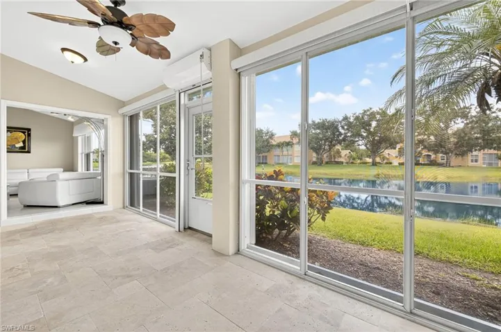 Unfurnished sunroom featuring a water view, stone tile floors, and vaulted ceiling