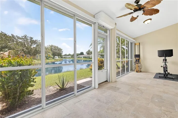 Unfurnished sunroom featuring a water view, stone tile flooring, and lofted ceiling