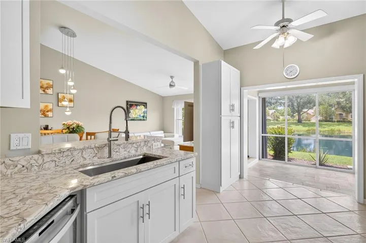 Kitchen featuring a ceiling fan, light stone countertops, white cabinetry, light tile patterned floors, and high vaulted ceiling