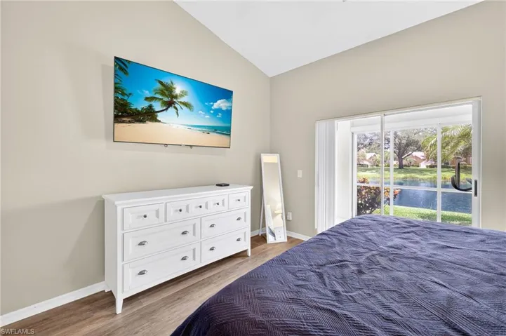 Bedroom with vaulted ceiling, wood finished floors, and access to exterior
