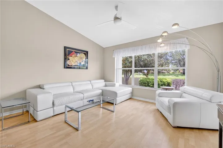 Living room with ceiling fan, vaulted ceiling, and wood finished floors