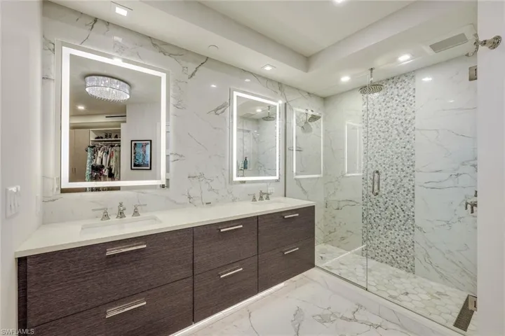 Floating underlit double vanity with beautiful lighted mirrors above. Marble flooring, and walls.  Mult shower head walk in shower.