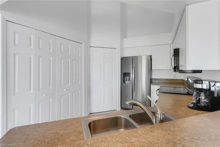 Kitchen with sink, a high ceiling, white cabinets, and appliances with stainless steel finishes