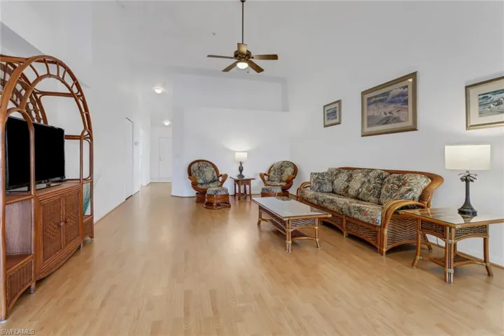 Living room featuring ceiling fan, light hardwood / wood-style flooring, and a high ceiling