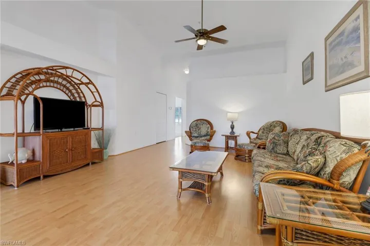 Living room featuring ceiling fan, light hardwood / wood-style flooring, and a towering ceiling