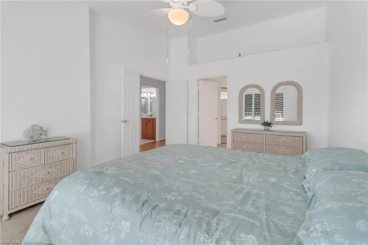 Carpeted bedroom featuring a towering ceiling, connected bathroom, and ceiling fan