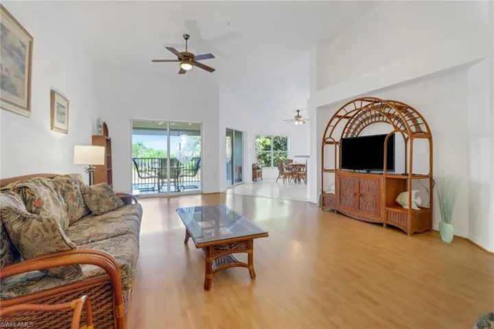 Living room featuring ceiling fan, light hardwood / wood-style floors, and a towering ceiling