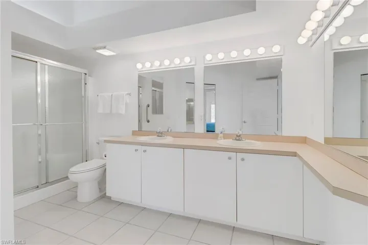 Bathroom featuring tile patterned flooring, vanity, a shower with shower door, and toilet