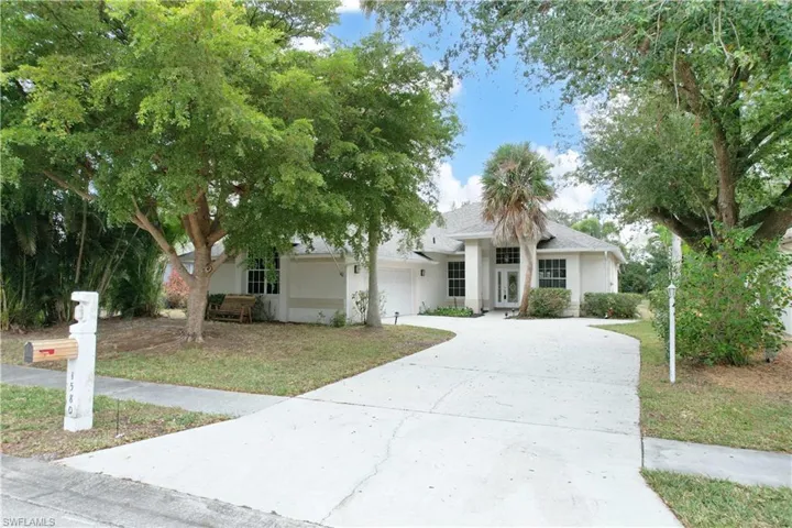 View of front facade with driveway, a garage, roof with shingles, a front lawn, and stucco siding