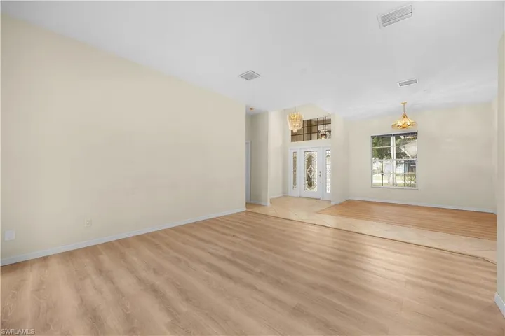 Unfurnished living room featuring light wood-style floors, a chandelier, and french doors