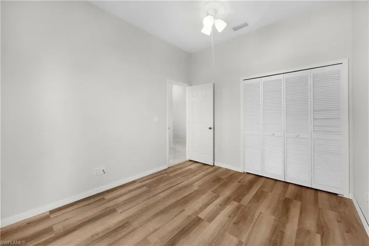 Unfurnished bedroom featuring light wood finished floors, a closet, a ceiling fan, and a high ceiling