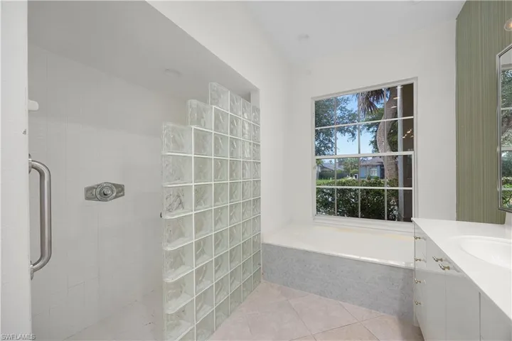 Full bath featuring a walk in shower, a bath, vanity, and light tile patterned floors