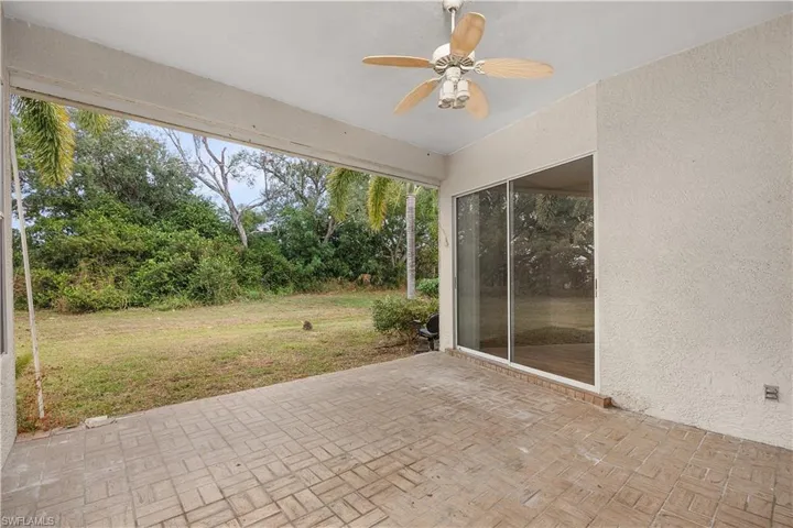 View of patio with a ceiling fan and view of wooded area