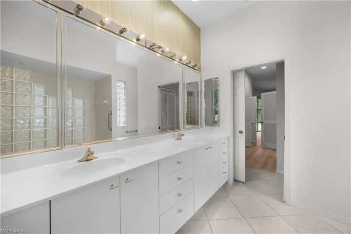 Bathroom with double vanity, light tile patterned floors, and a shower with door