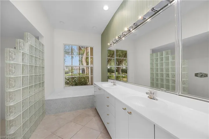 Bathroom with light tile patterned floors, a bath, double vanity, walk in shower, and recessed lighting