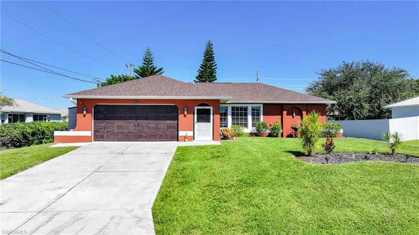 Single-story residence featuring a terracotta-colored stucco exterior, a dark wood-finish garage door, a concrete driveway, and white-framed multi-pane windows