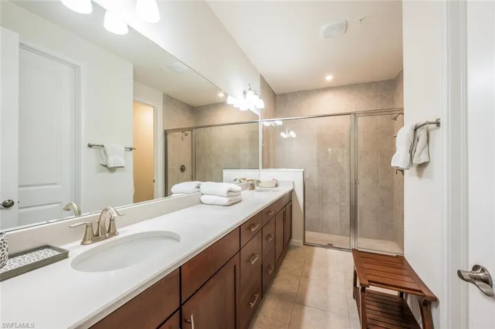 Full bathroom with double vanity, tile patterned floors, and a stall shower